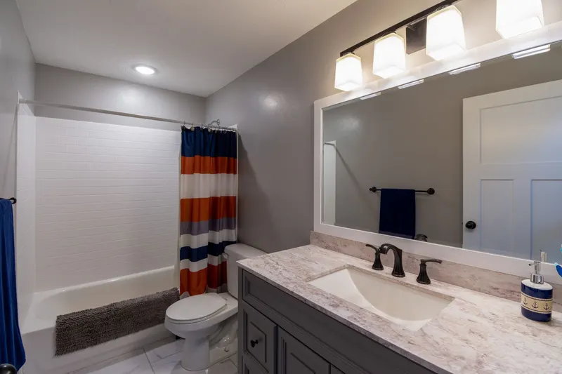 A bathroom remodel featuring a bathtub, toilet, and vanity with a marble countertop.
