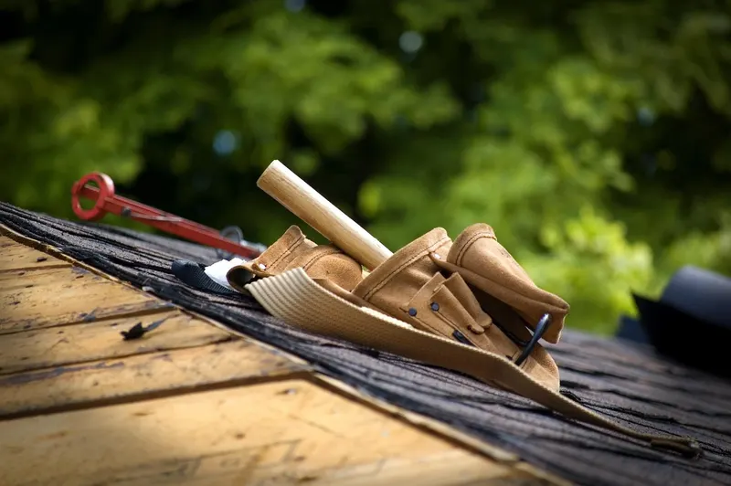 Roofing tools and a tool belt on a shingled roof.